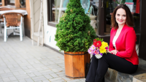 Smiling woman in red blazer with bouquet of flowers on her lap