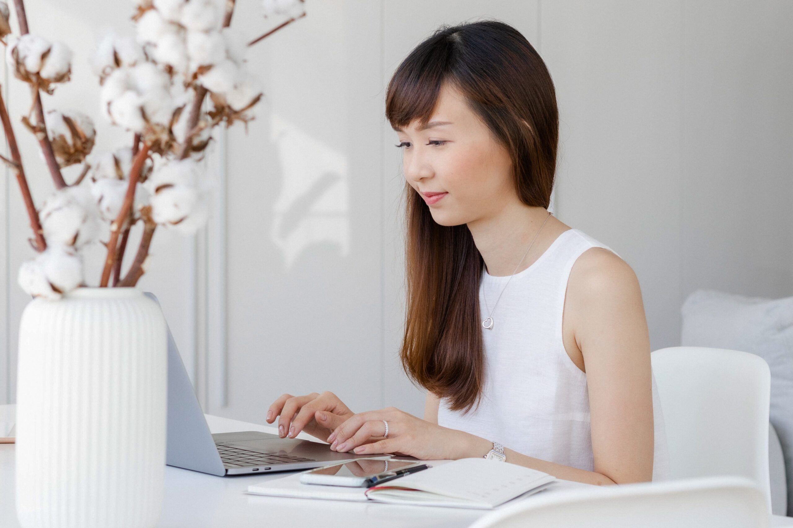 Woman smiling at laptop taking online video coaching lesson at her desk