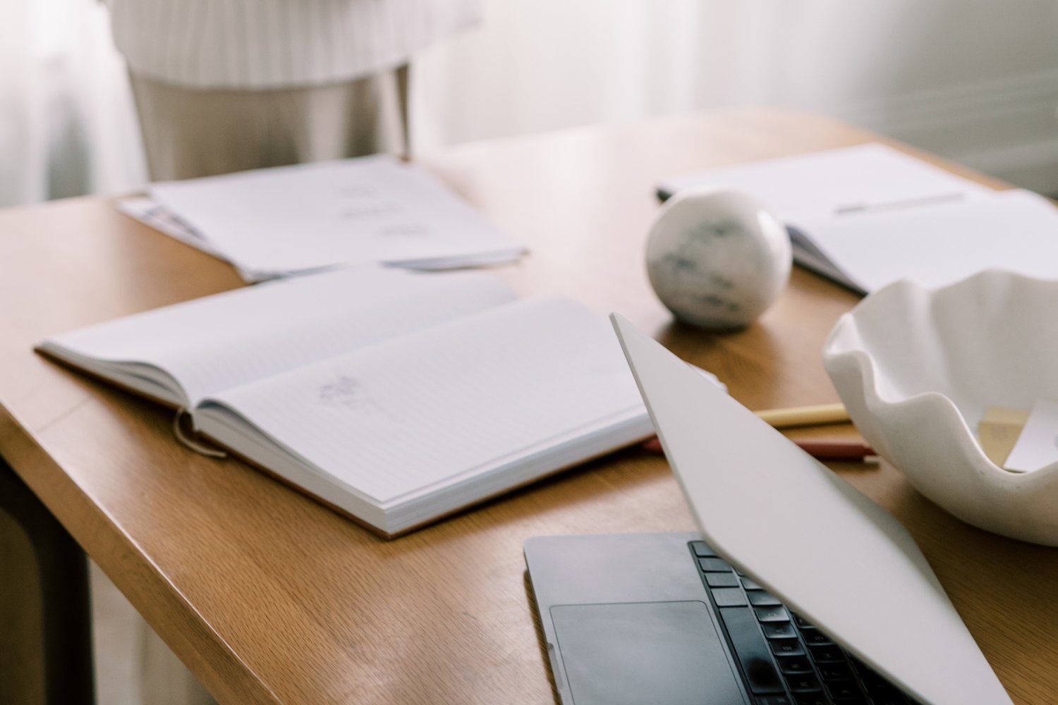 Open notebook and documents on a desk beside a cup of coffee.