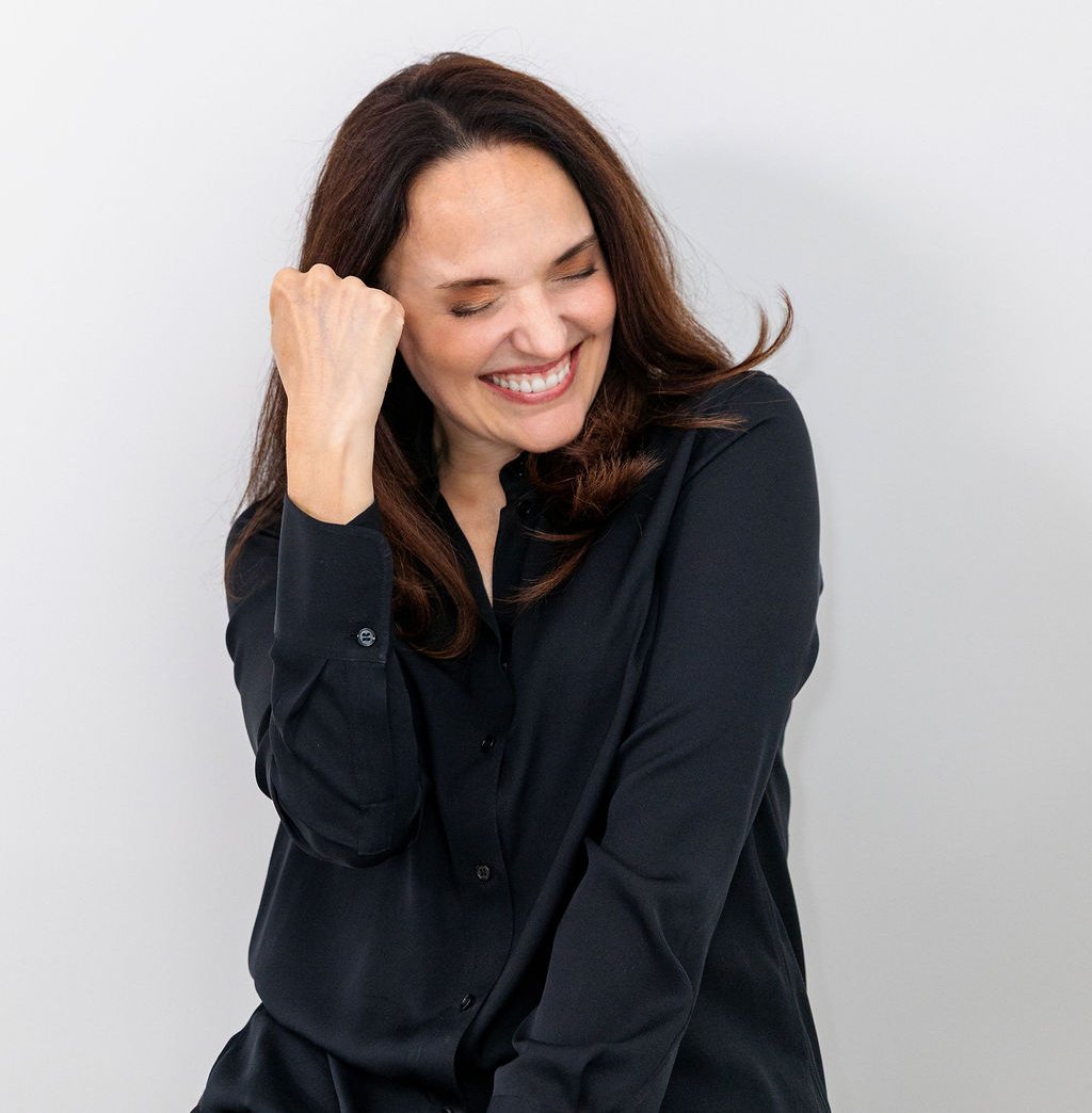Sarah Walton smiling with her hand in saying 'Yes', wearing a black top