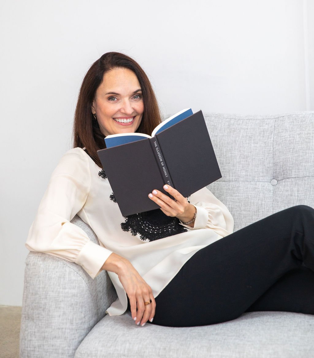 Sarah Walton smiling on a couch while holding a book