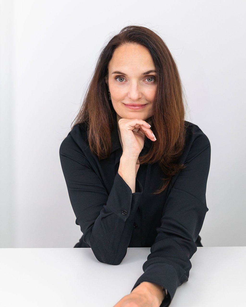 Sarah Walton leaning forward with her chin resting on her hand, wearing a dark shirt.