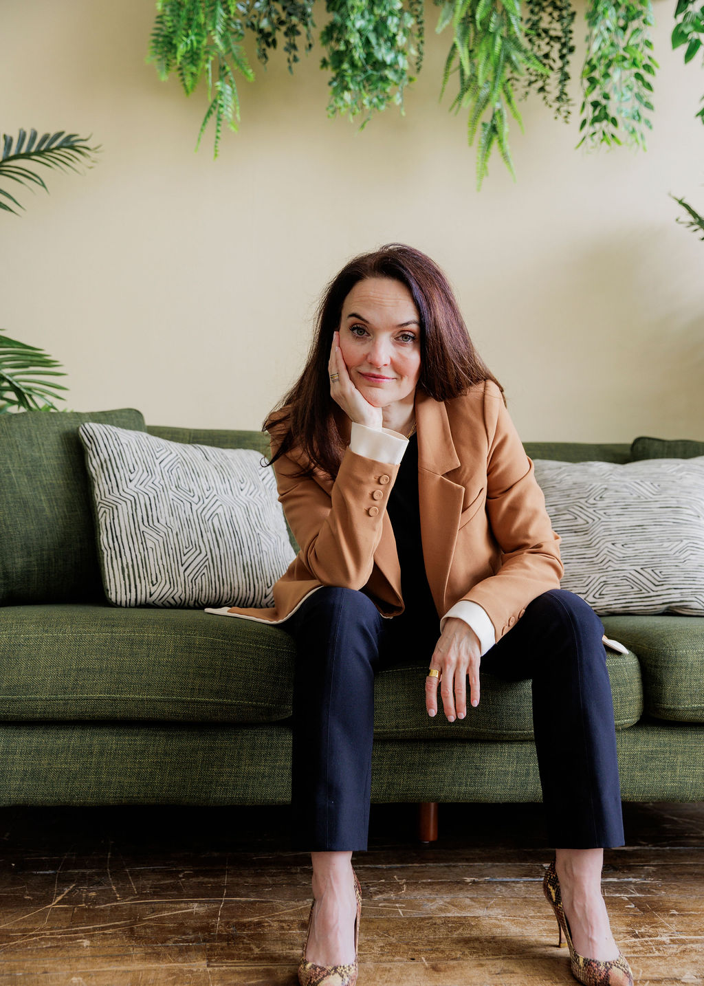 Sarah Walton sitting on a green couch with her hand on chin.