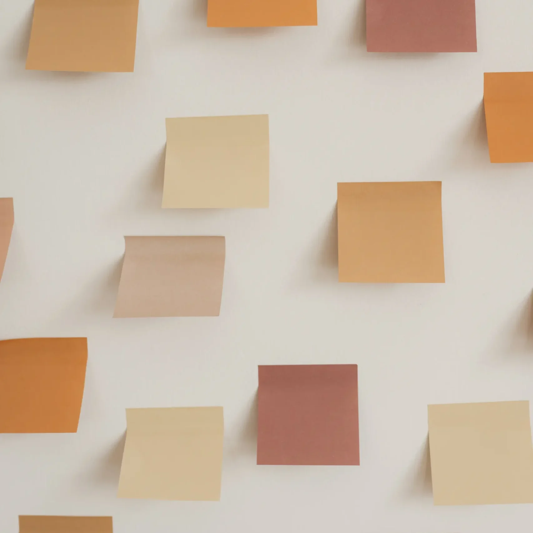 Earth-toned post-it sheets stuck on a white wall.