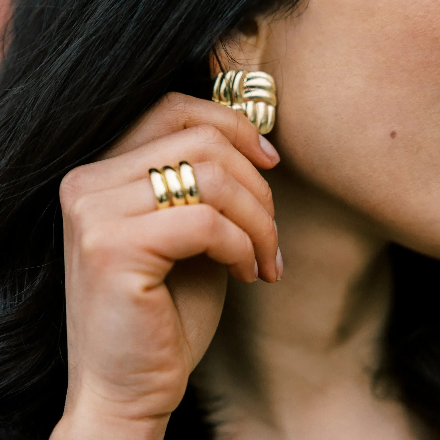 Profile of woman wearing a gold ring and gold earring.