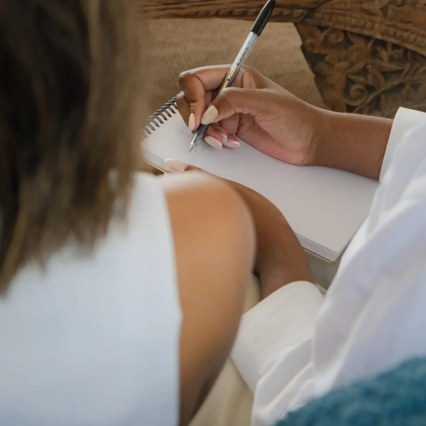 Tow women sitting at a workshop, one writing in journal